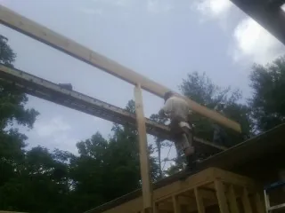 Carpenter setting a ridge beam over a new addition frame — Ice Dam Removal by Roofing Brothers in Penn Yan