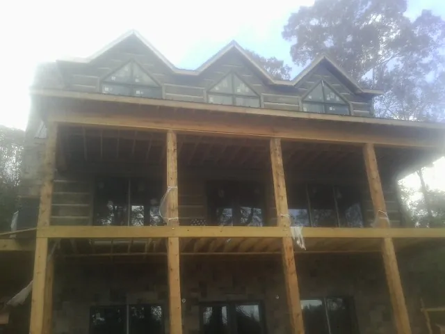 Dormers and porch framing on a large log home under construction — Roof Coating work by our crew in Penn Yan