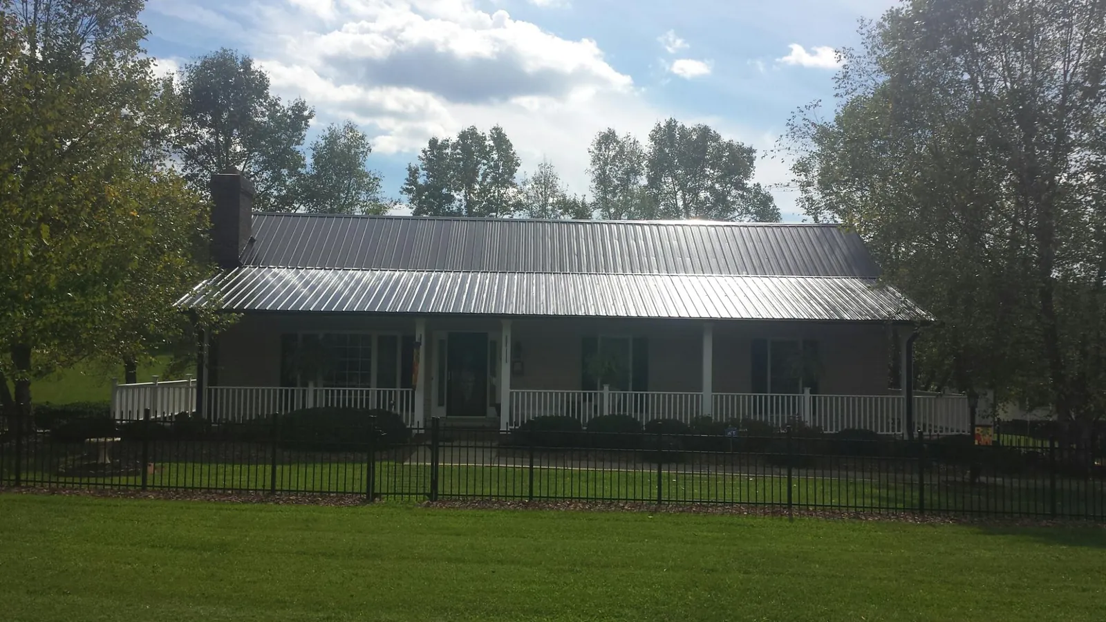 Gray metal roof on a brick ranch with a full width front porch — Gutter Guard Installation work by our crew in Penn Yan