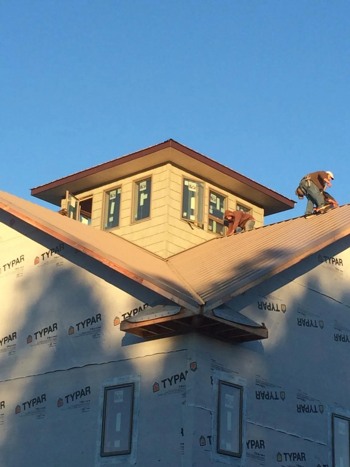 Roofers working around a rooftop cupola on a new metal roof at sunset — Roof Waterproofing in Penn Yan by Roofing Brothers